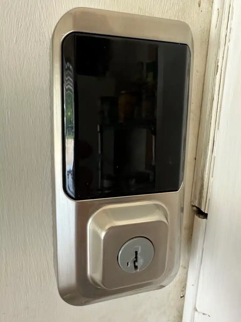 A close-up of a modern electronic door lock with a keypad and a traditional keyhole installed on a white door.