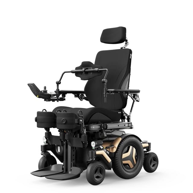 A black motorized wheelchair with adjustable headrest, armrests, leg supports, and joystick control, featuring large rear wheels and a metallic frame.