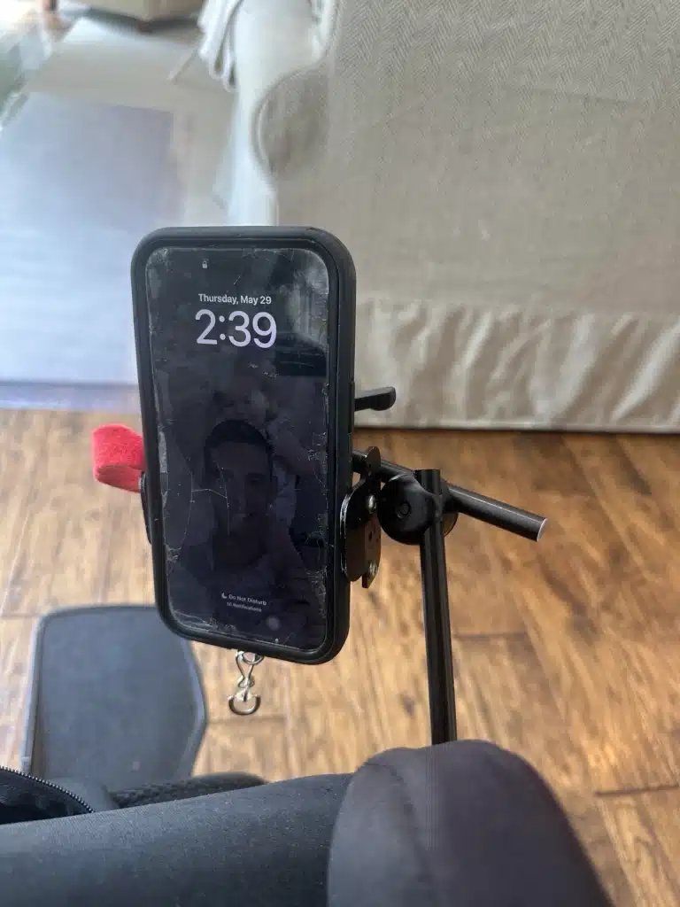 A smartphone mounted on a holder attached to a wheelchair. 